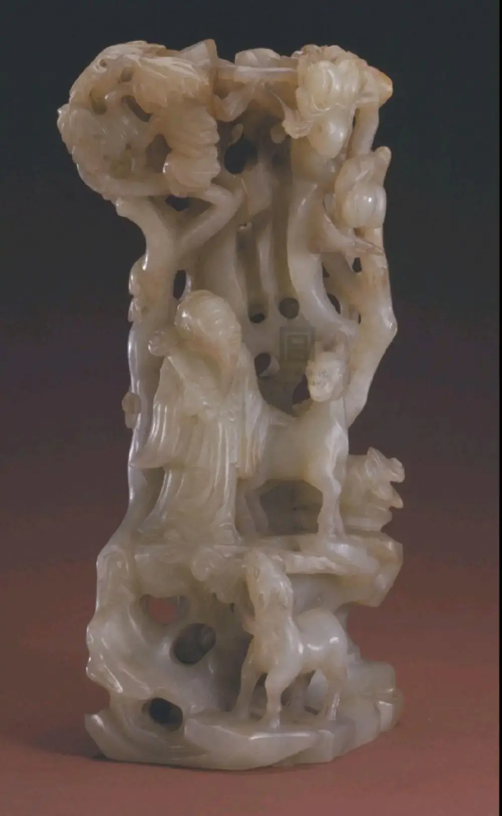 明代 玉寿鹿山子 故宫博物院藏品
玉寿鹿山子，明，高14.8厘米，宽9厘米。清宫旧藏。
山子玉料青绿色，雕立体山林景致。作品下部为山石，其上高树成荫，并结有桃实，树下一老人当风而立，著长袍短褂，左手轻抚身旁小鹿，右手持如意，崖下又有一小鹿，口衔灵芝，仰首面向石上的老人。