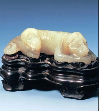 明代 青玉卧狗 故宫博物院藏品
青玉卧狗，明，高1.5厘米，长5.4厘米
青玉质，圆雕。狗呈半趴卧状，前爪对合，后爪蜷缩于身下。背部凸雕出明显的脊骨，脊骨两侧用简练的阴线刻画出肋骨。
明代的玉狗较之清代显得…