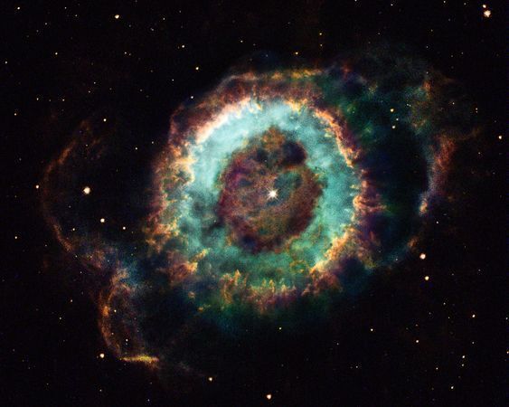 小幽灵星云NGC 6369是很多业余天文学家的最爱。从地球上观察，它是一个黯淡气体云，环绕一颗恒星尸体，座落于蛇夫星座。在这幅“哈勃”2004年拍摄的照片中，小幽灵星云展示了其更多细节，揭示了已死恒星放射出的气体的演化。恒星产生的紫外辐射剥离气体中的原子，让附近区域离子化，形成明亮的蓝绿环。外缘的红色区域离子化程度相对较低。