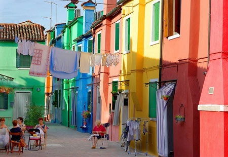  【Burano 布拉諾島】是義大利威尼斯潟湖上的島嶼，以手工蕾絲和彩色房子聞名於世。據說1481年達芬奇從希臘小城鎮Lefkara購回米蘭大教堂使用的壇布後，引進了花邊蕾絲，此技術於該島上生產製作，日後逐漸成為當地特產。彩色的房子其實最初是為了辨識家門的標示，居民確定顏色後必須向政府申請通過，才能彩繪，不同樣顏色的小房子並列，形成像童話故事裡才會有的彩色世界，相當可愛。