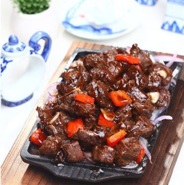 材料 嫩肩牛肉 红椒 蚝油 盐 绍酒 鸡蛋 洋葱 黑胡椒 生抽 白糖 <br />淀粉 <br />大蒜 作法1.将嫩肩牛肉切成块，进行腌制， 腌制入味的牛肉片加入生抽、黄酒、清水、淀粉、鸡蛋清、拌匀，表面淋入净植物油，入冰箱保鲜室，冷冻约3 小时以上备用；2.洋葱切细丝，红椒切块，锅烧热后锅内做油，放入洋葱丝煸炒出香味；3.洋葱炒7成熟取出一半放在烧热的铁板上，另一半待用；4.锅烧热放油6成热放入牛肉粒迅速滑熟，盛出控油；5.炒锅上火烧热，加入黄油熬化后，放入蒜片，煸香后放黑胡椒末稍煸；6.加入蚝油、黄酒、生抽、砂糖、盐、熬开。。。。。。