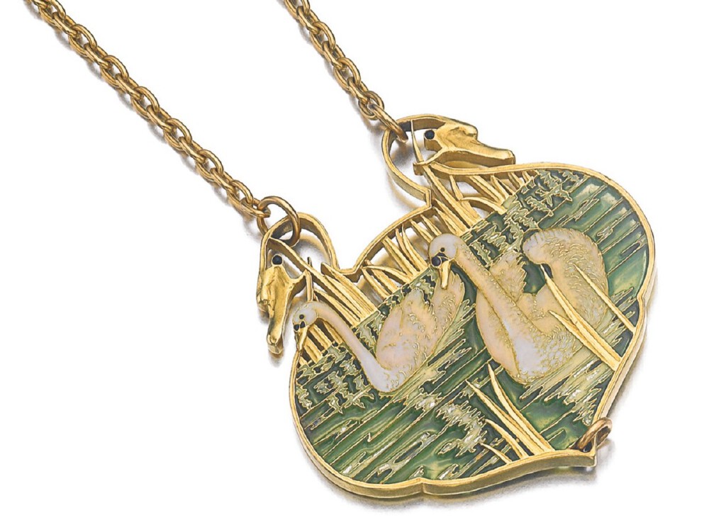 The pendant designed as two swans in a pond, decorated with iridescent enamel, suspended from a fine link chain, length approximately 610mm, signed Lalique, French assay and maker’s marks.