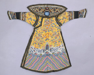 明黄缂丝彩云金龙纹女绵朝袍·前式。清嘉庆，身长139cm，两袖通长174cm，袖口21cm，下摆118cm，开裾长81cm。清宫旧藏。 朝袍圆领，大襟右衽，马蹄袖，袖、身相接处有接袖，有披领、护肩，左右开裾。袍以“通经断纬”…